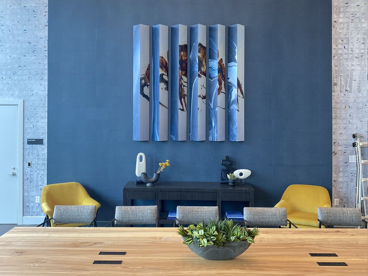Modern abstract slatted art on a blue wall above a seating area