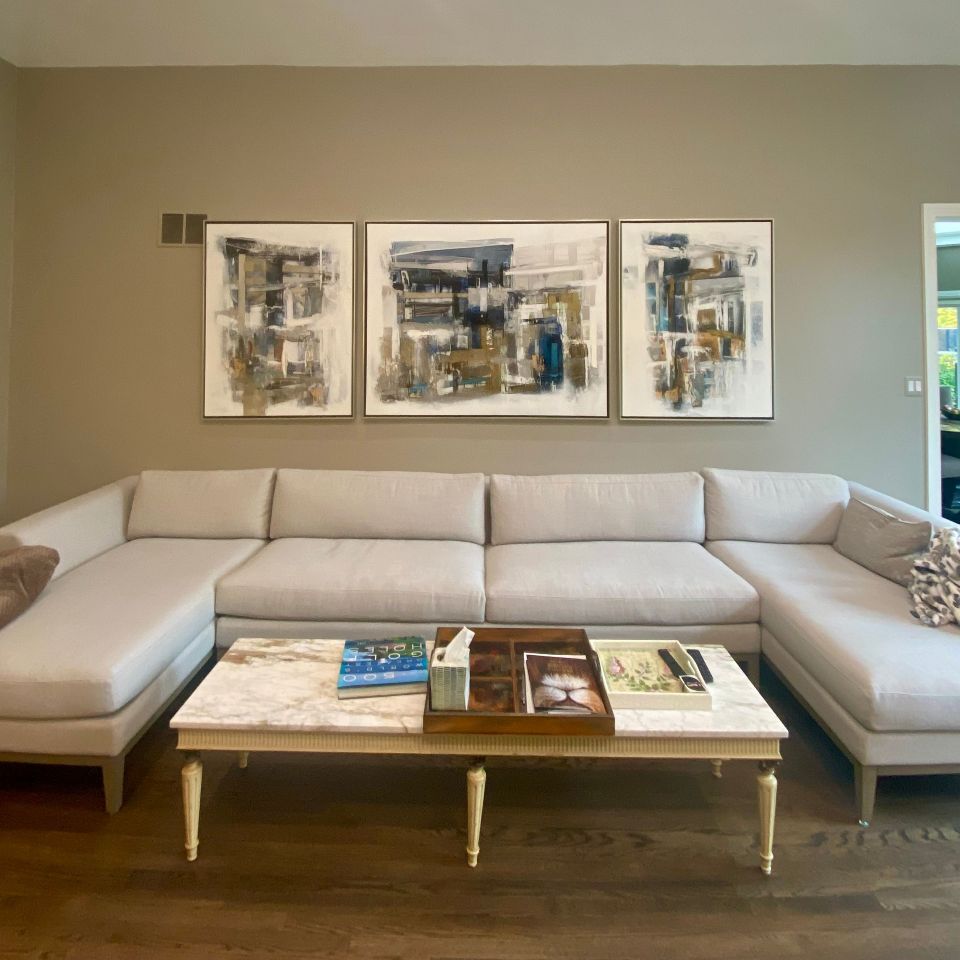 Three pieces of abstract art framed and hung above a modular sofa