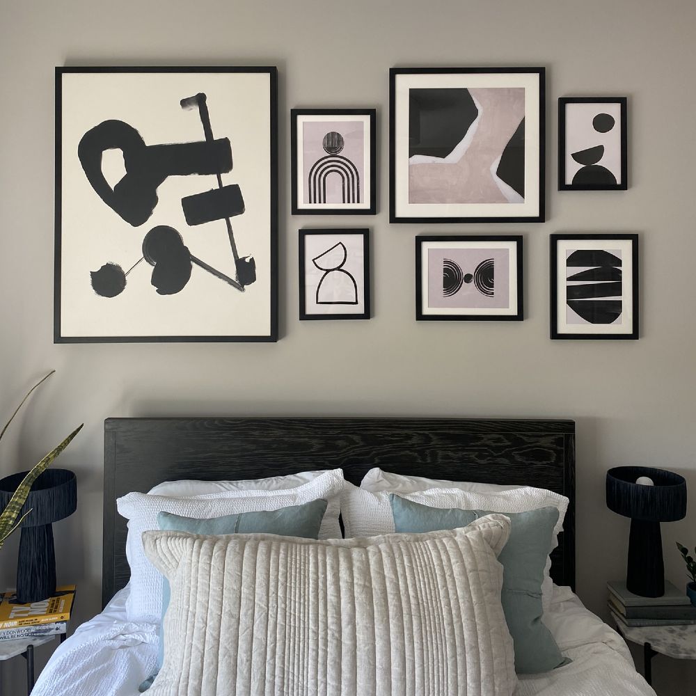Cluster of different sized pieces of abstract art above a bed