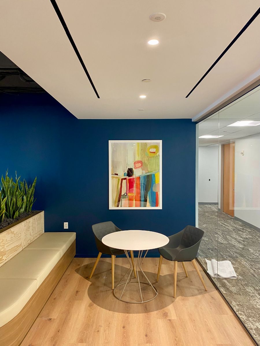 A framed abstract print hung above a table and chairs in a commercial building
