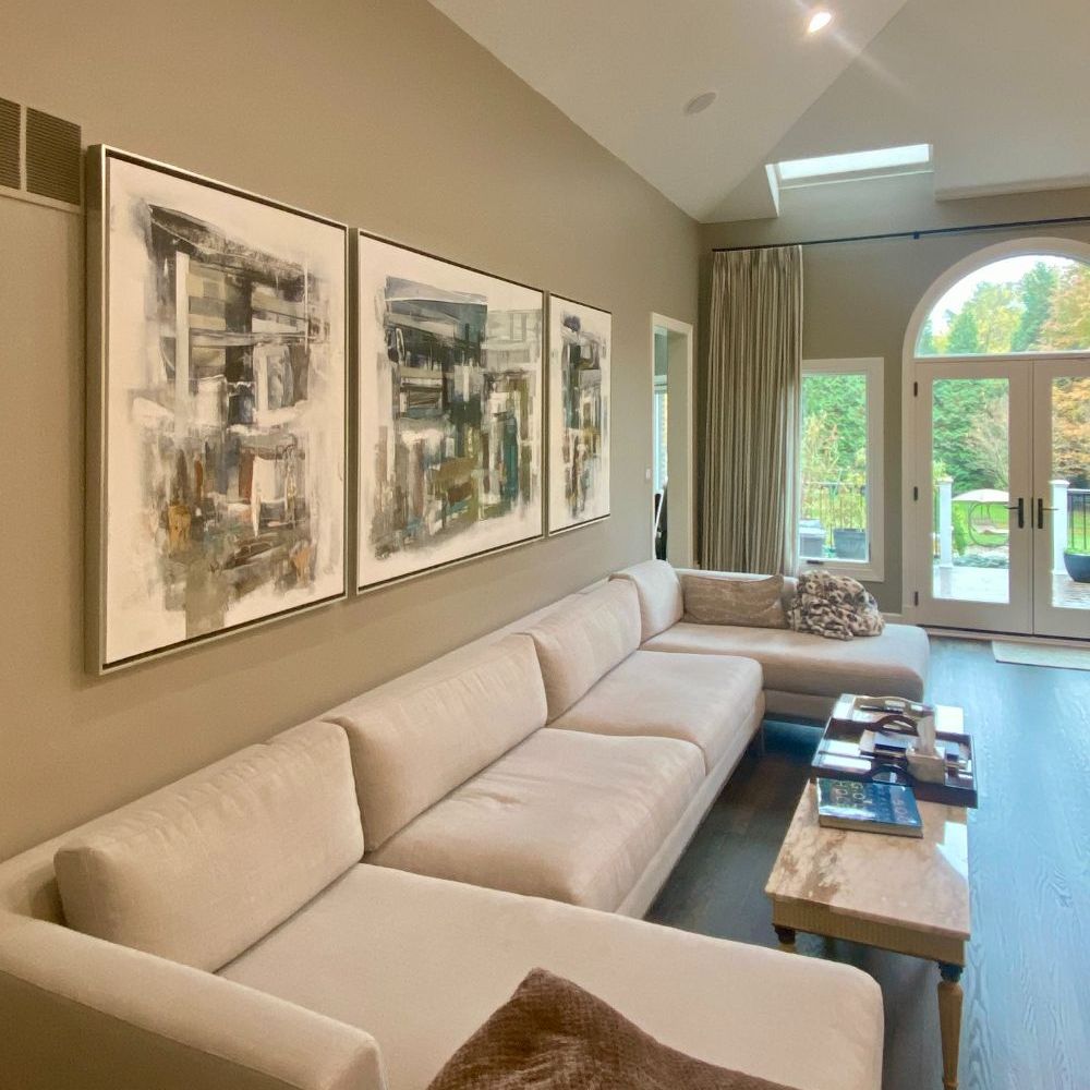 Three pieces of abstract art framed and hung above a modular sofa